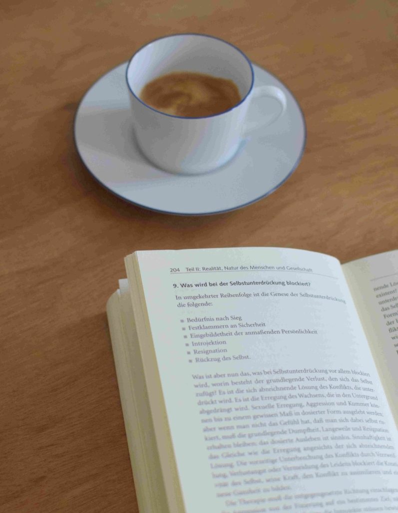 Kaffeetasse und Psychotherapiebuch für Fachwissen und Qualifikation